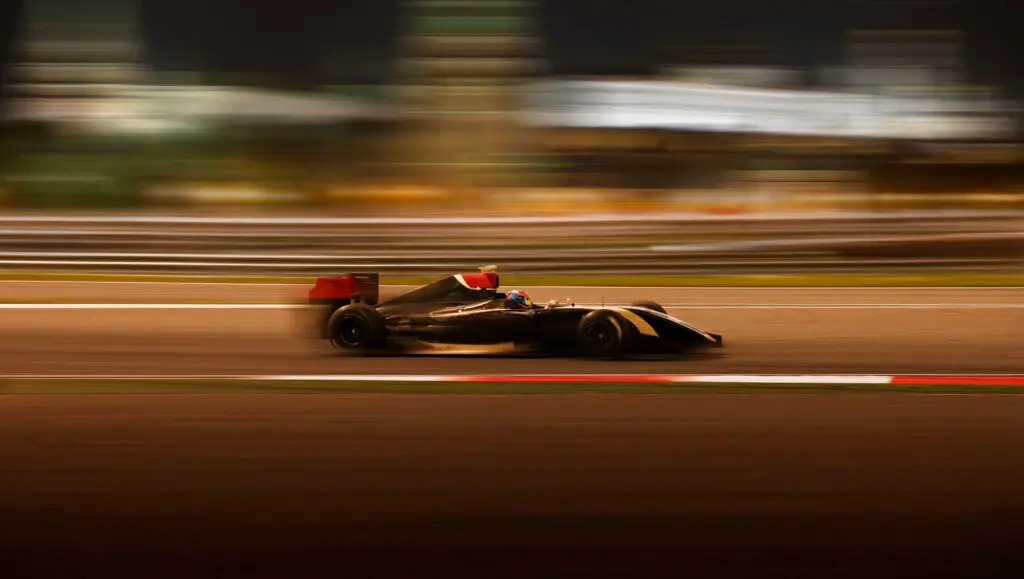 Formula 2.0 race car racing at high speed with motion blur on the background of the city in the dark
