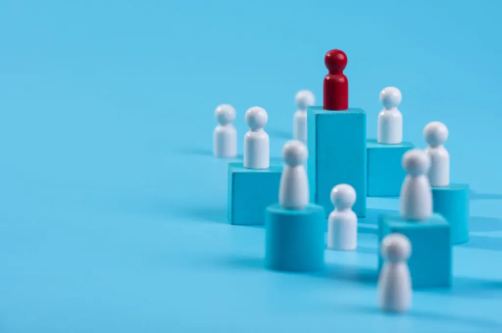 Red wooden figure standing on wooden podium for business leadership for team leader concept.