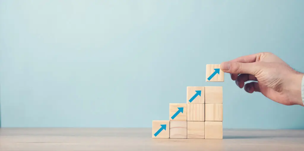 Man hand arranging wood block stacking as step stair