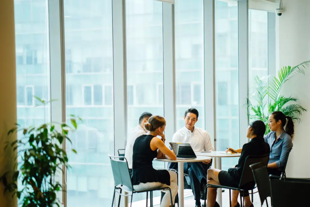 A diverse team sits around a table in a meeting room