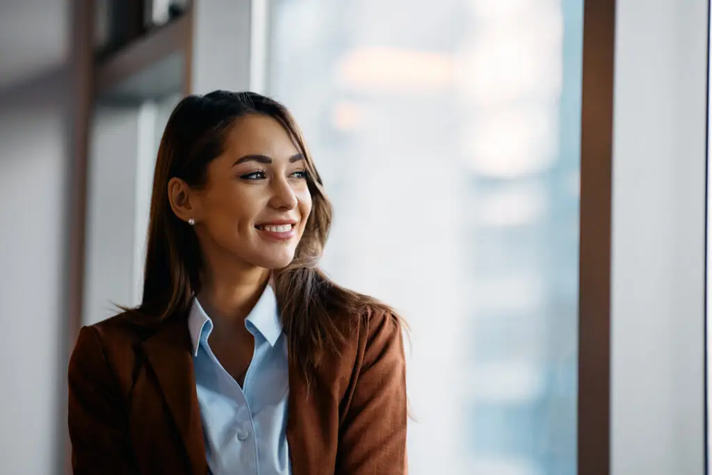 Portrait of young happy businesswoman in office looking away.